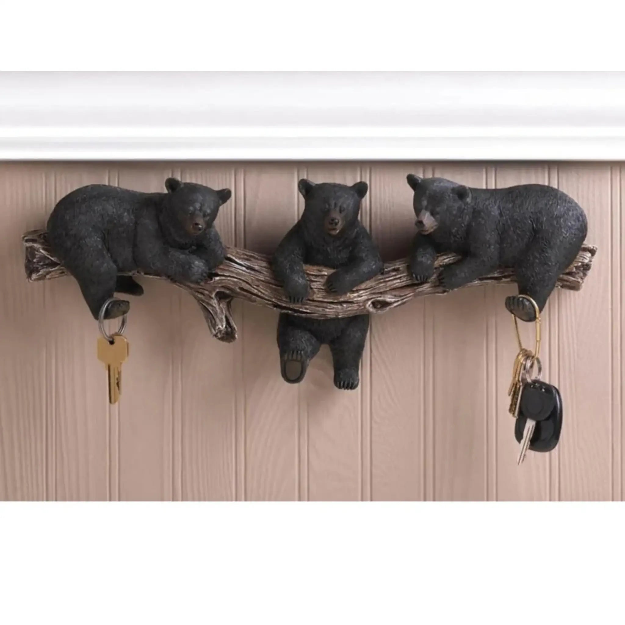 Wall-mounted key holder with bear figurines on a wooden background