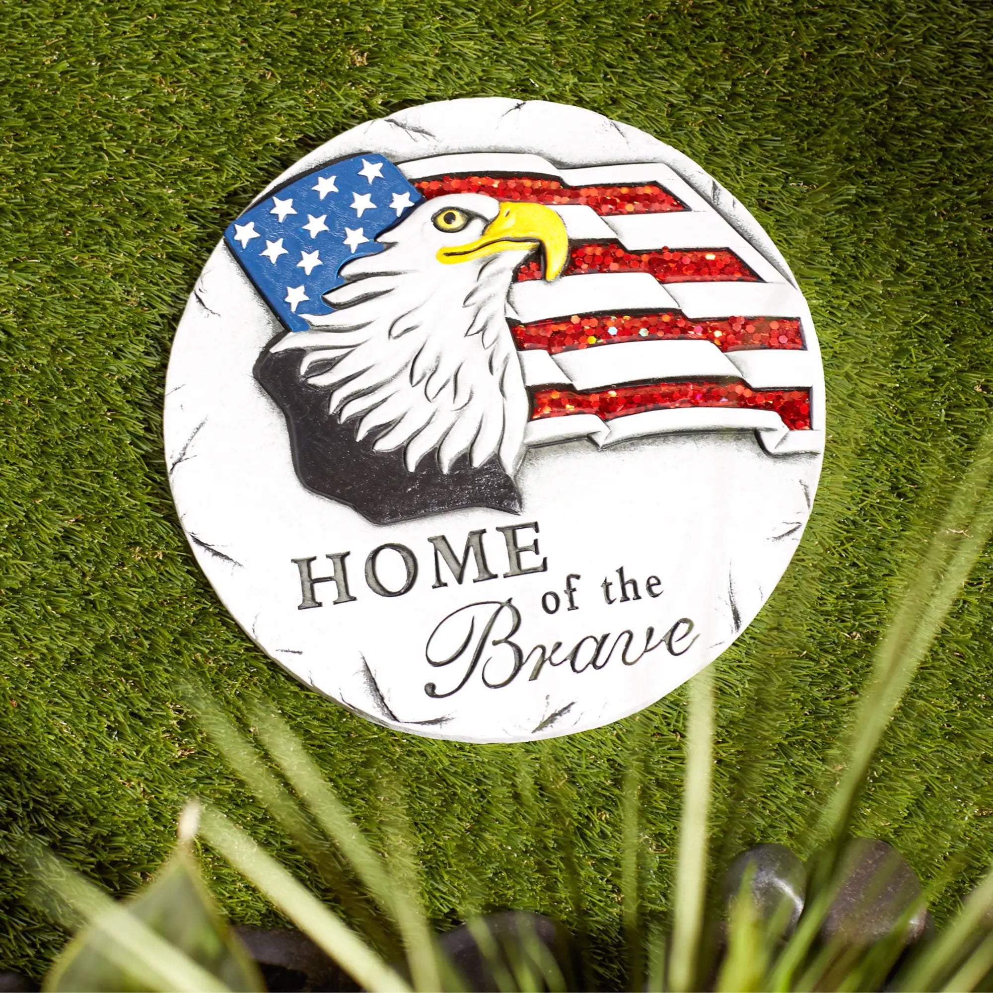 Garden stepping stone with an eagle and American flag design on a grassy background