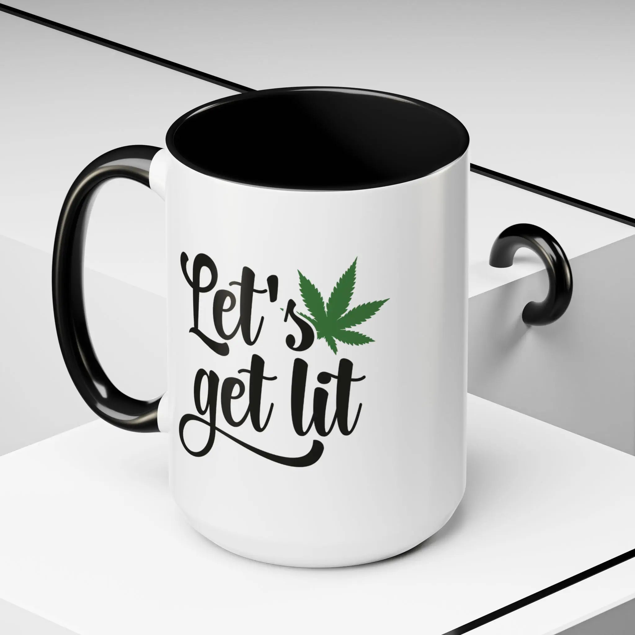 White ceramic mug with black handle and black interior featuring the phrase “Let’s get lit” with a green cannabis leaf design.