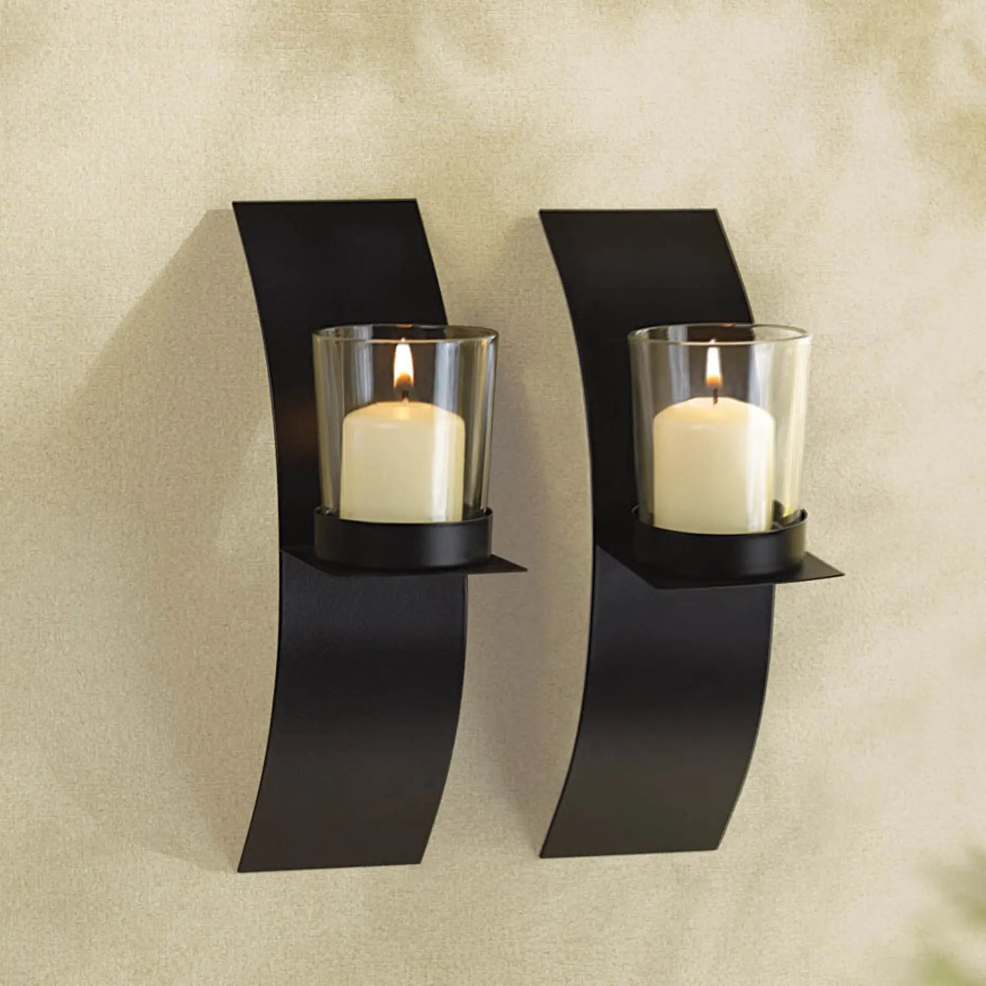 Two black wall sconces with glass candle holders on a beige wall.