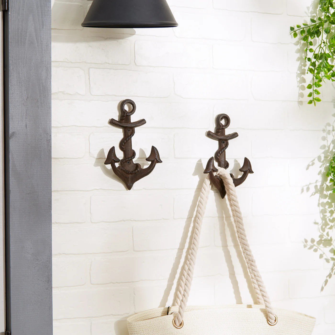 Set of 2 cast iron anchor wall hooks holding a tote bag in a coastal-inspired entryway.