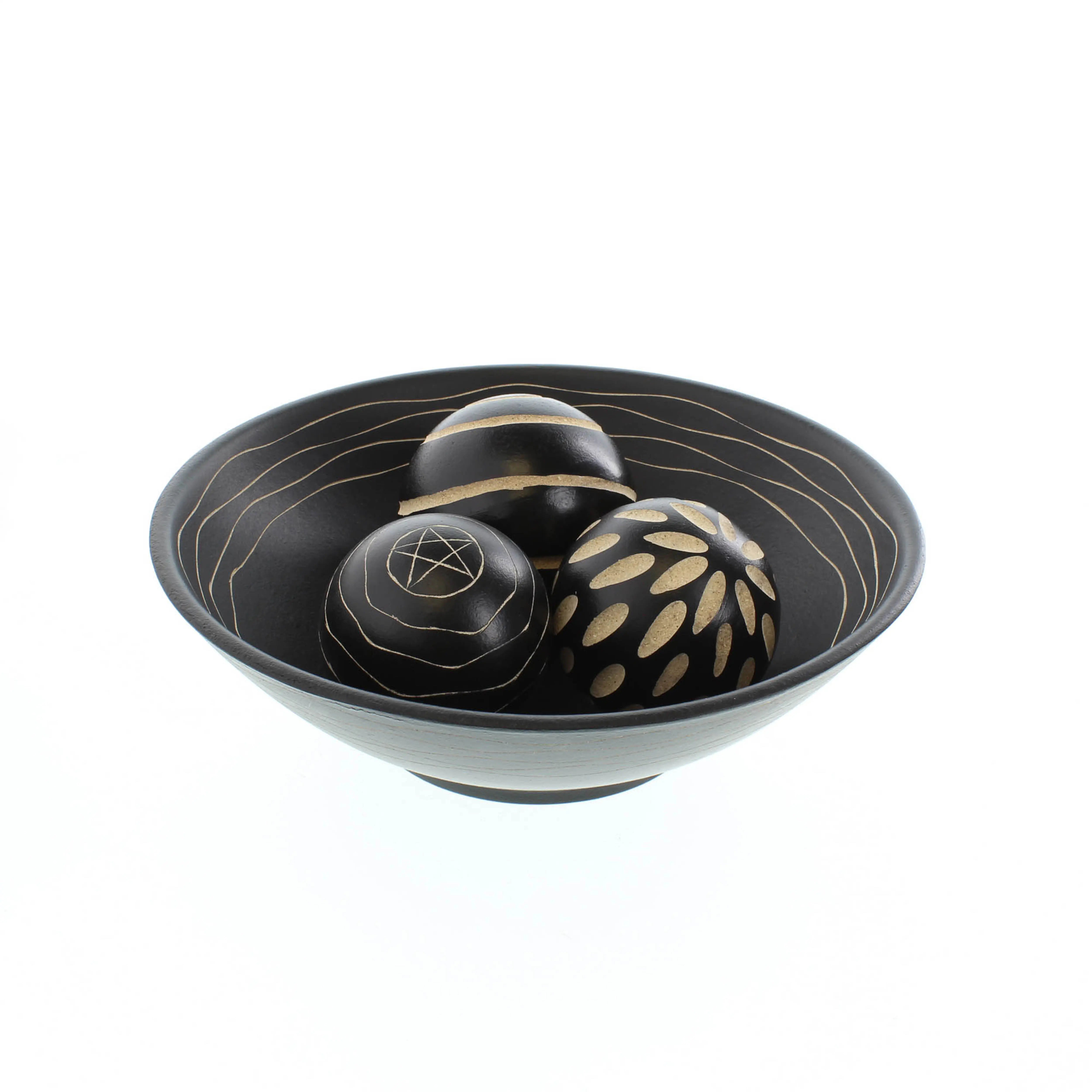 Black decorative bowl with three matching carved balls on a white background