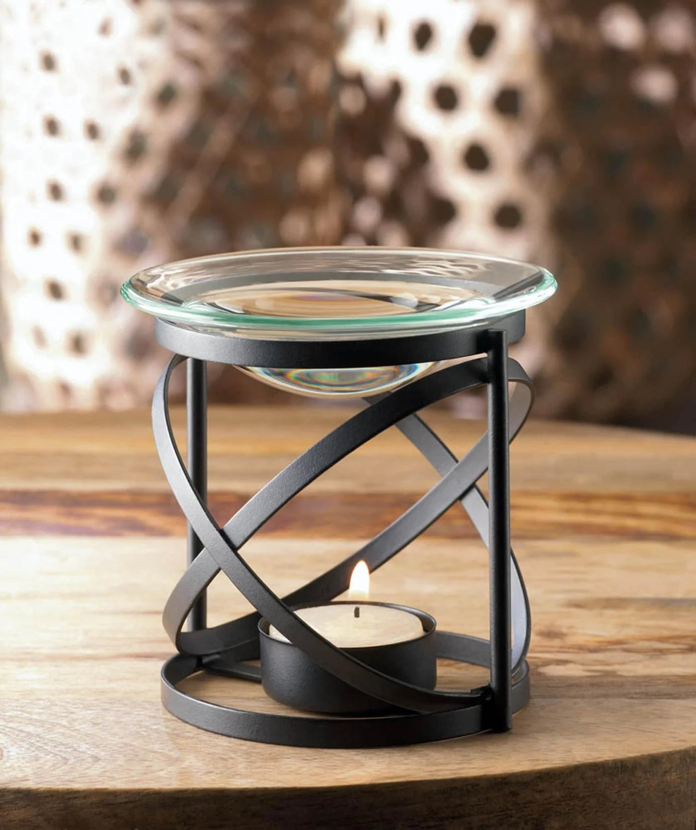 Orbital glass essential oil warmer with black metal frame and lit tealight candle