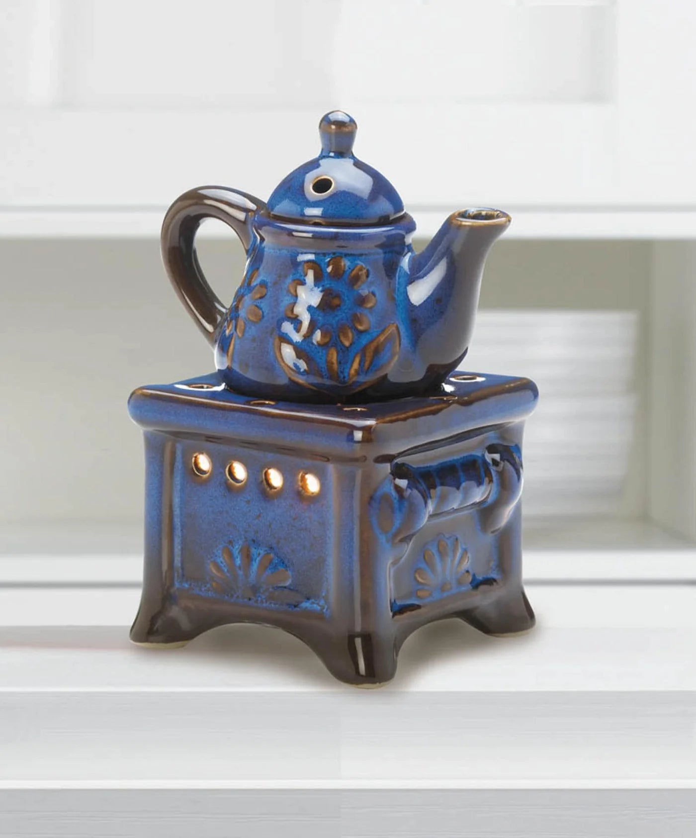 Blue teapot porcelain essential oil warmer glowing on a shelf