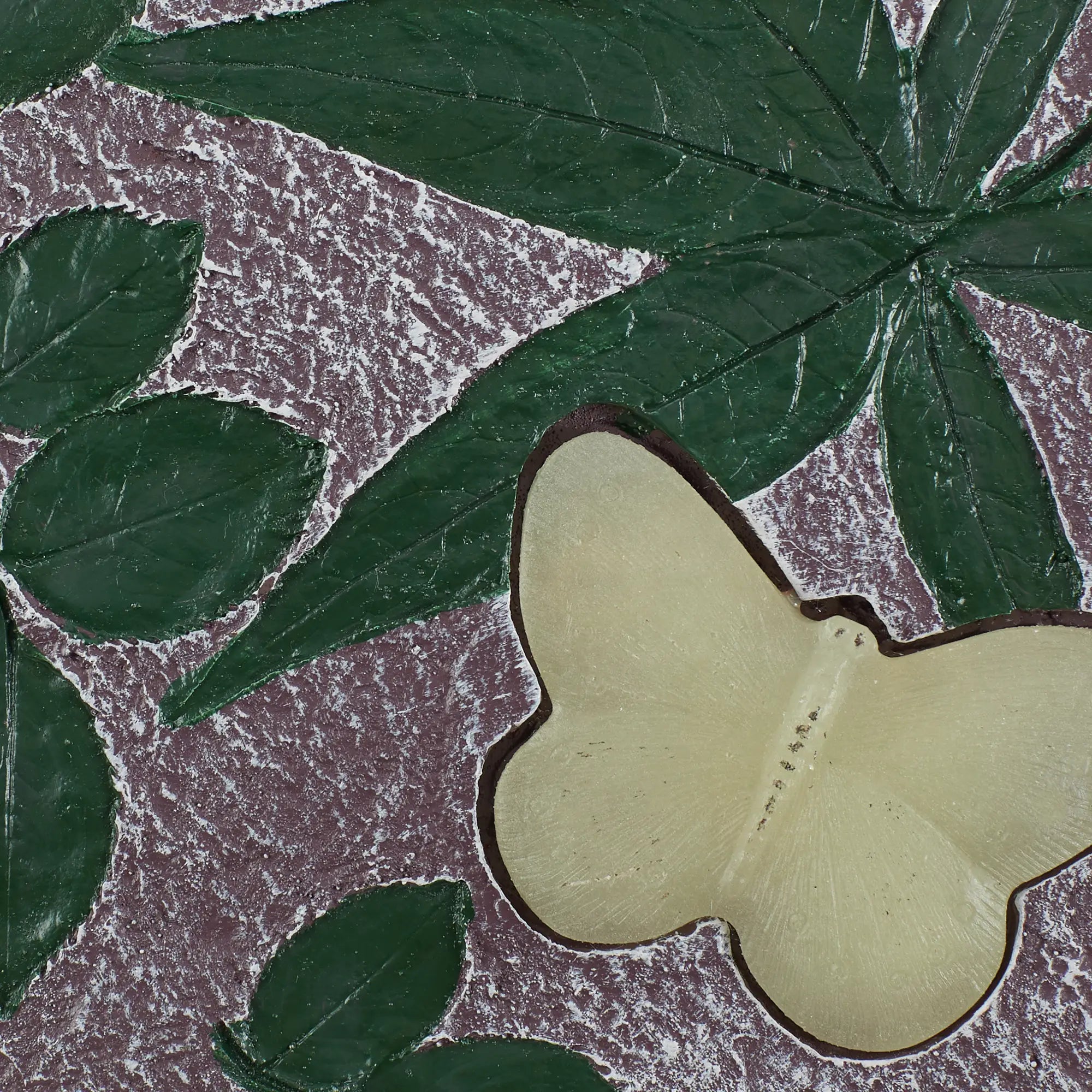 Close-up of green leaves and a yellow butterfly on cement garden stepping stone