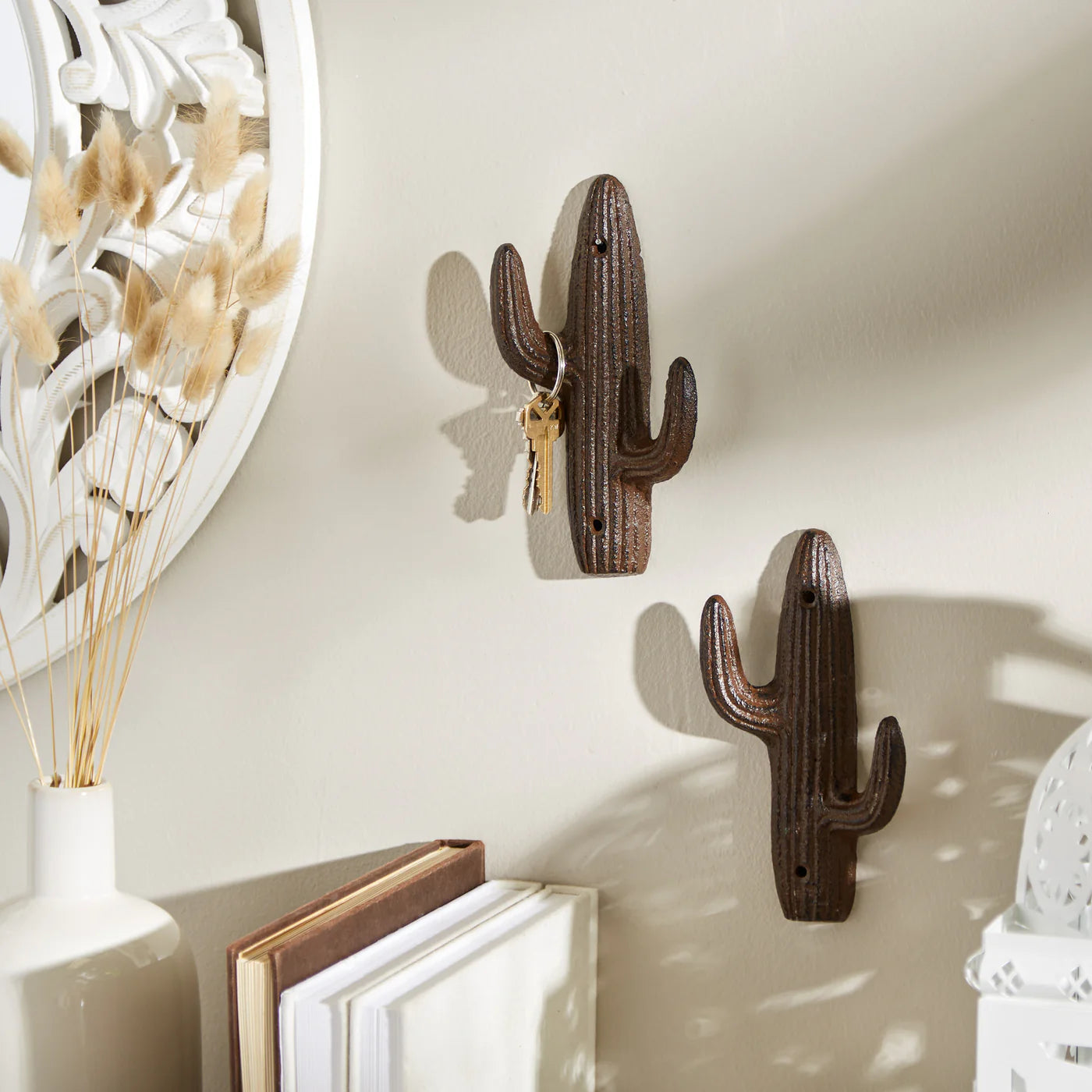 Cast iron cactus wall hooks mounted on a wall holding keys in a rustic Southwest entryway.