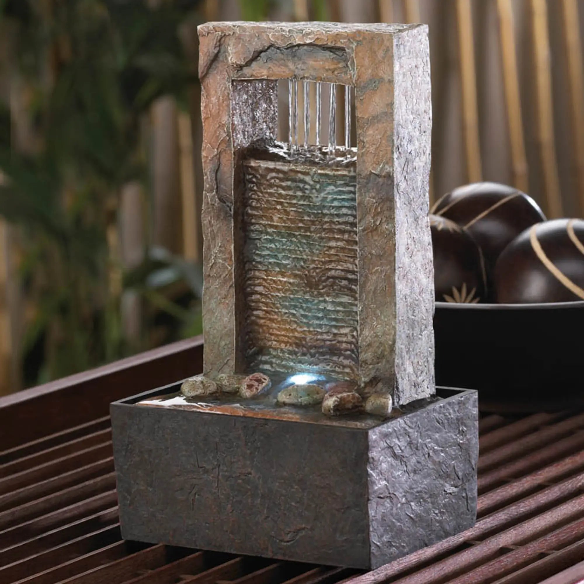 Decorative stone water fountain on a wooden surface with a blurred natural background