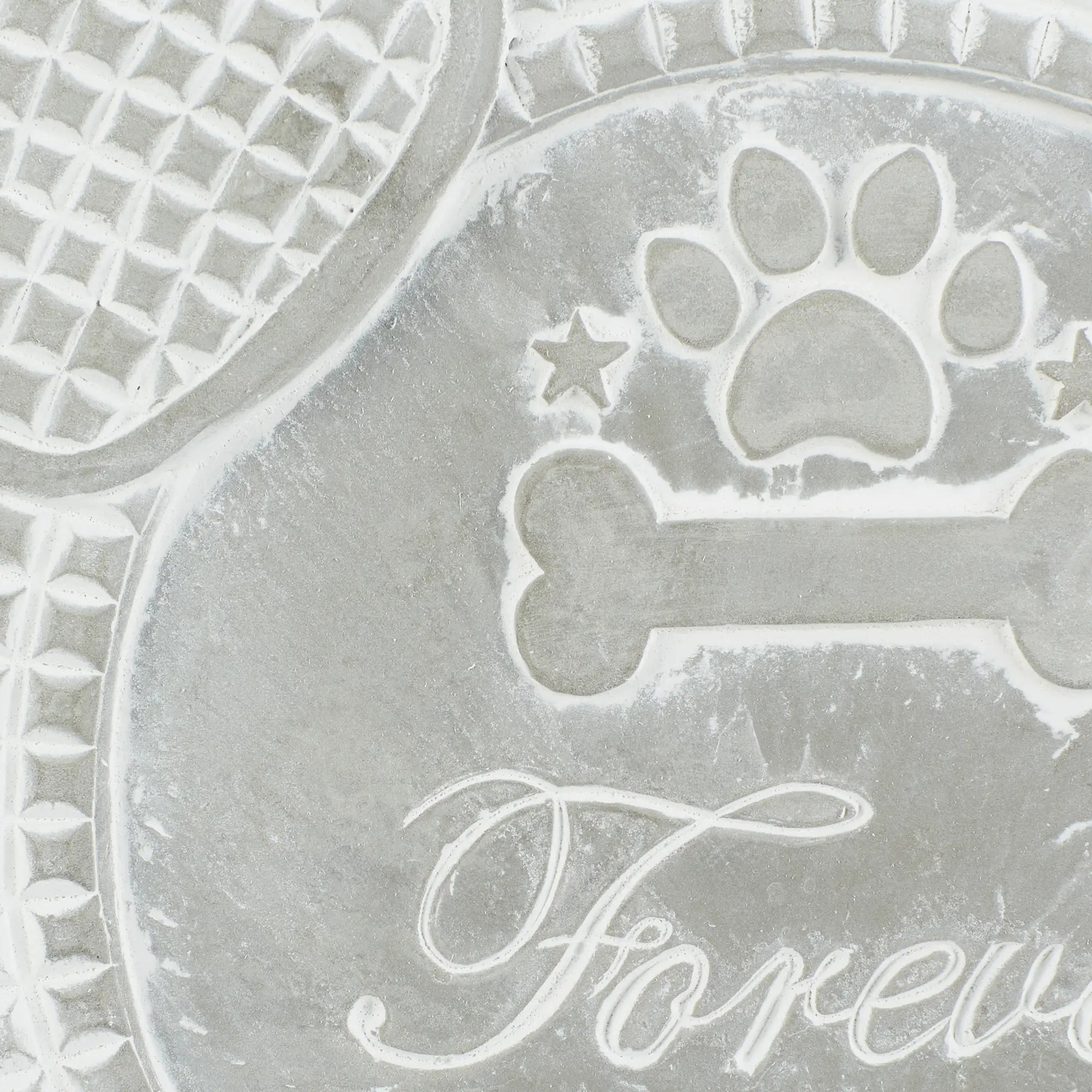 Close-up of paw print, bone, and Forever text on dog memorial cement stepping stone