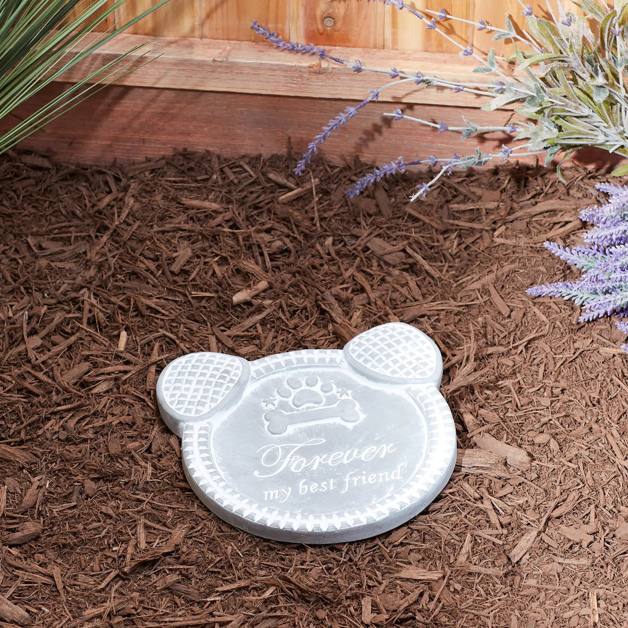 Paw-shaped dog memorial cement stepping stone with engraved text on mulch