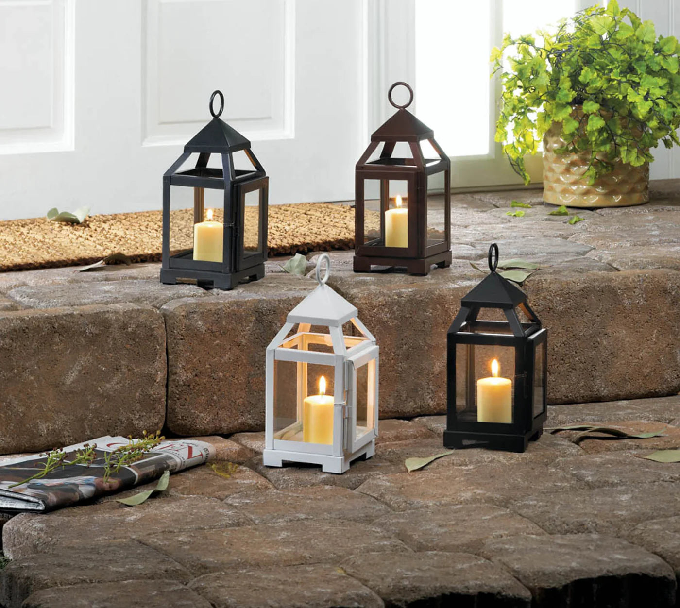 Set of four lanterns with candles on a stone surface outdoors.