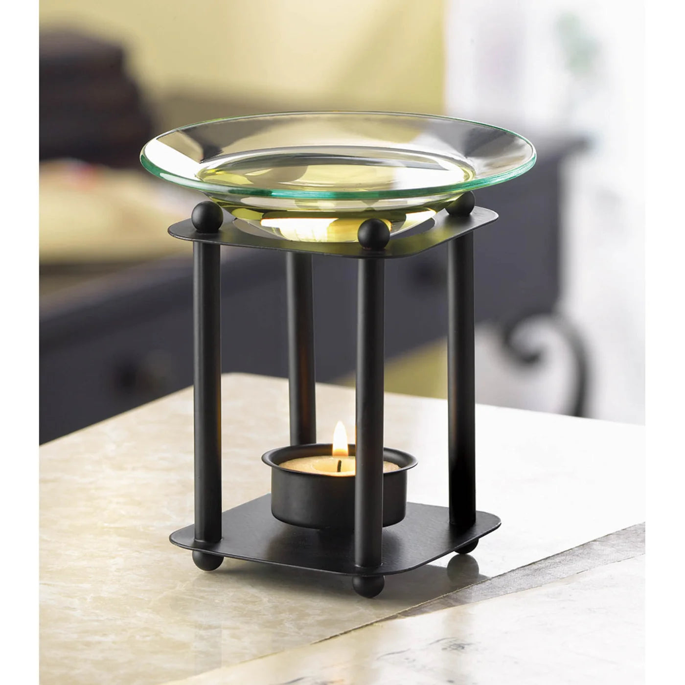 Glass essential oil warmer in use with a lit tealight candle on a table
