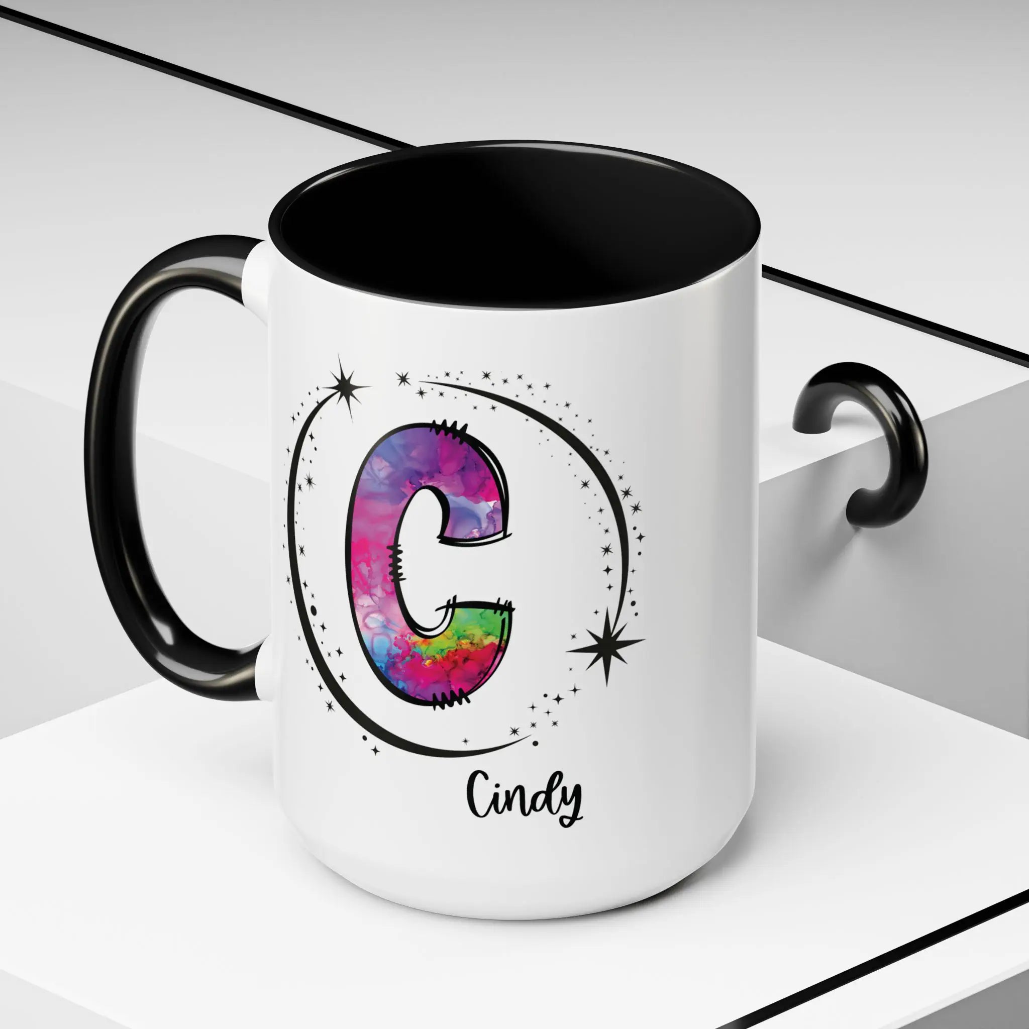 White monogram mug with black handle and interior featuring a colorful letter C design and custom name on decorative background