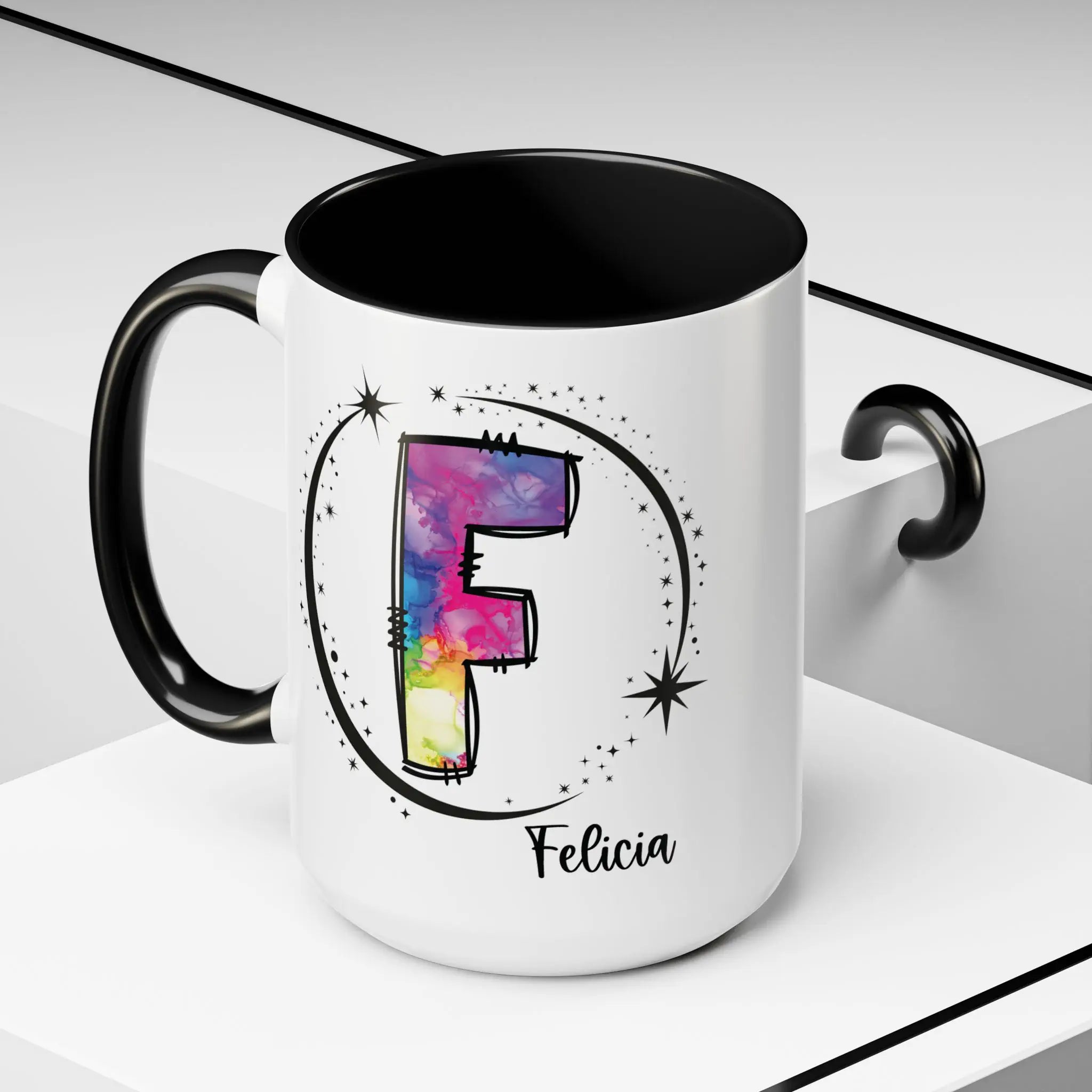 White monogram mug with black handle and interior featuring a colorful letter F design and custom name on decorative background