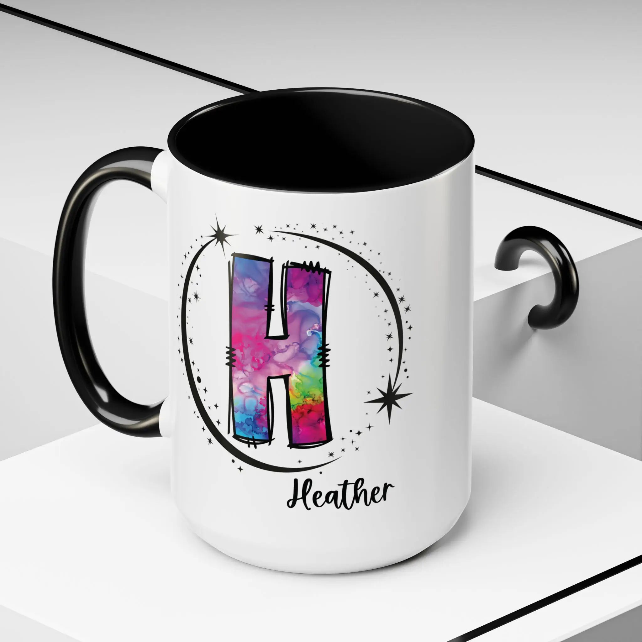 White monogram mug with black handle and interior featuring a colorful letter H design and custom name on decorative background