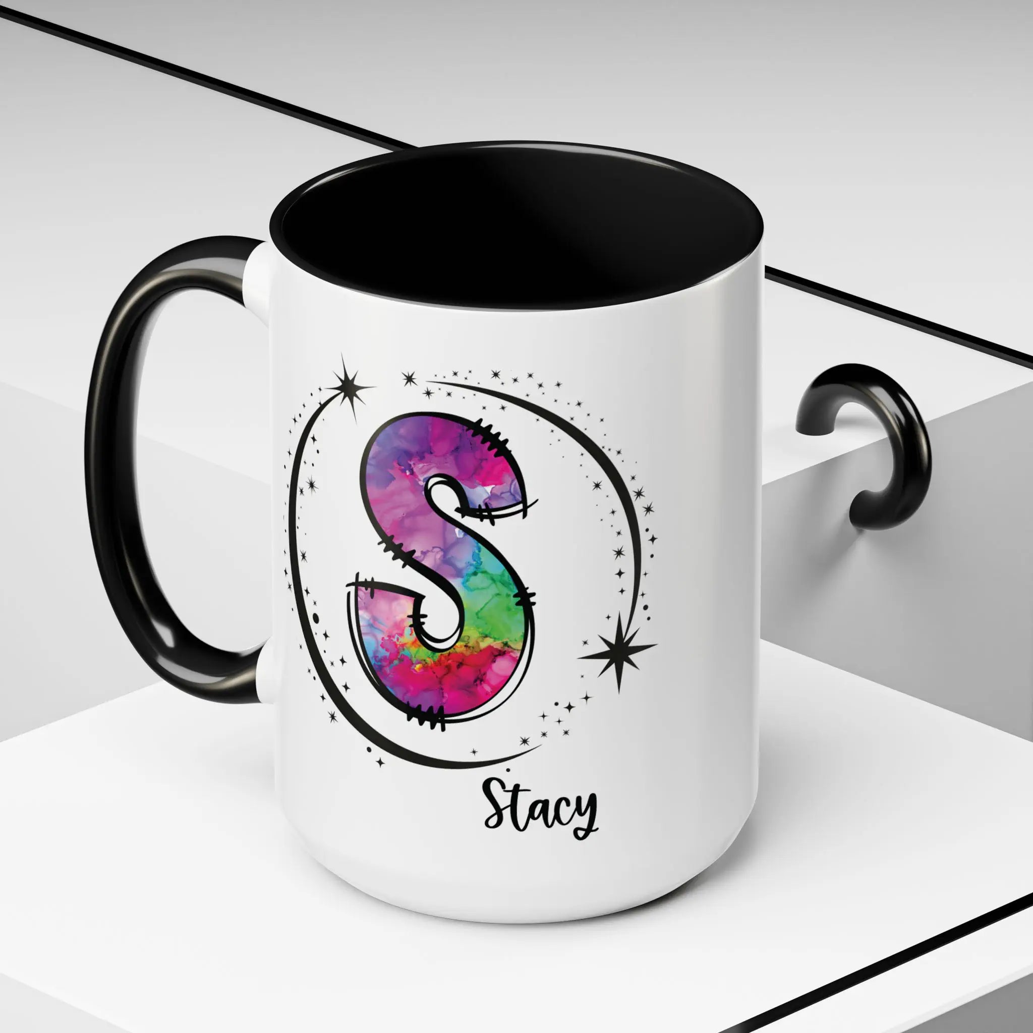 White monogram mug with black handle and interior featuring a colorful letter S design and custom name on decorative background
