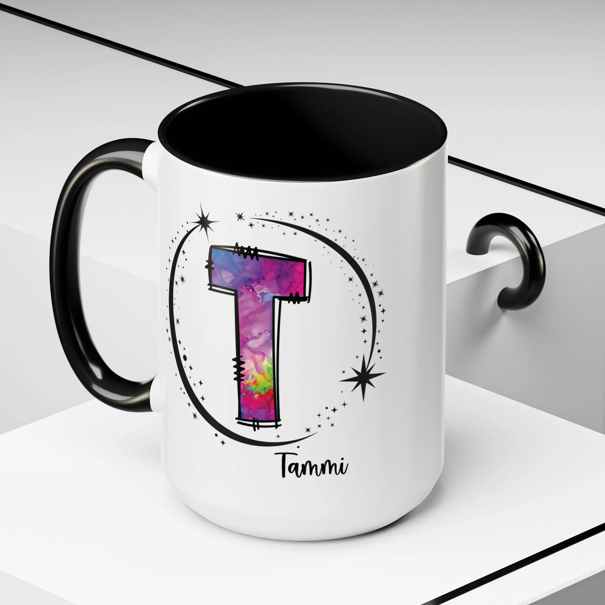 White monogram mug with black handle and interior featuring a colorful letter T design and custom name on decorative background