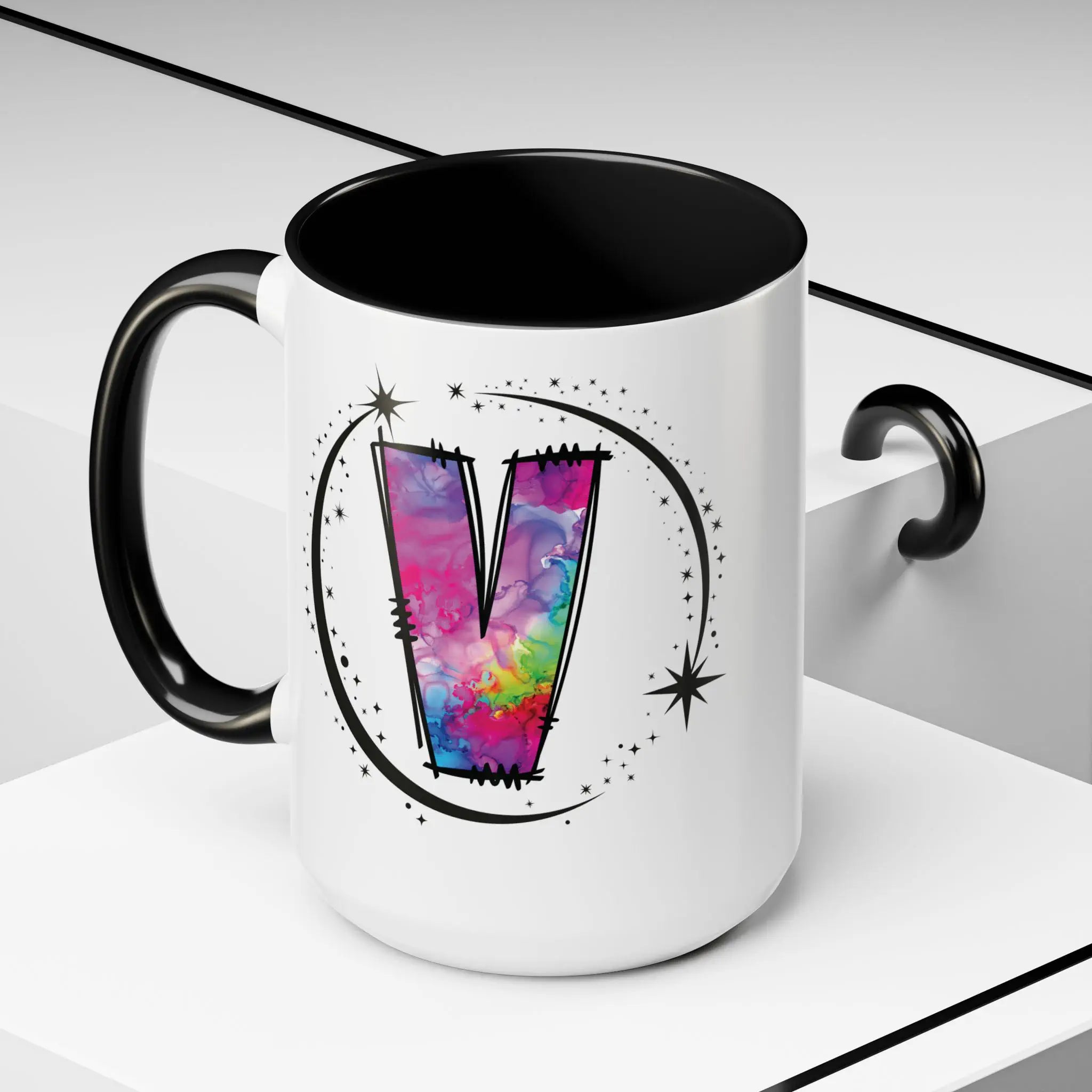 White monogram mug with black handle and interior featuring a colorful letter V design and custom name on decorative background