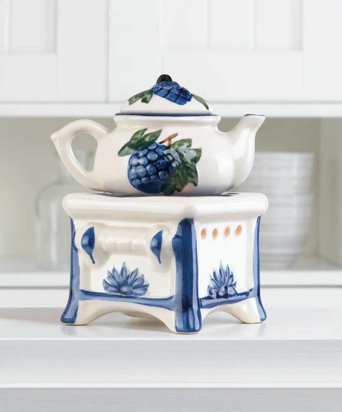 White porcelain teapot oil warmer with blue grape details glowing on a shelf